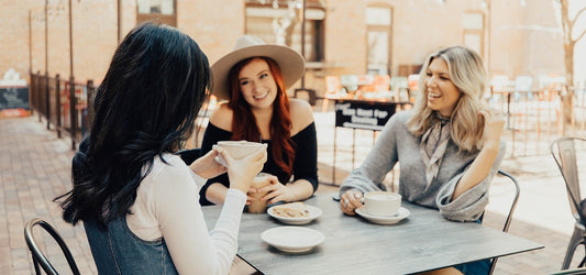 3 women sitting at table having coffee and laughing with TYME curls