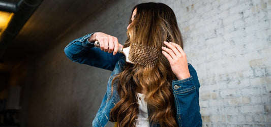 Woman brushing hair with TYME paddle brush Long brown hair